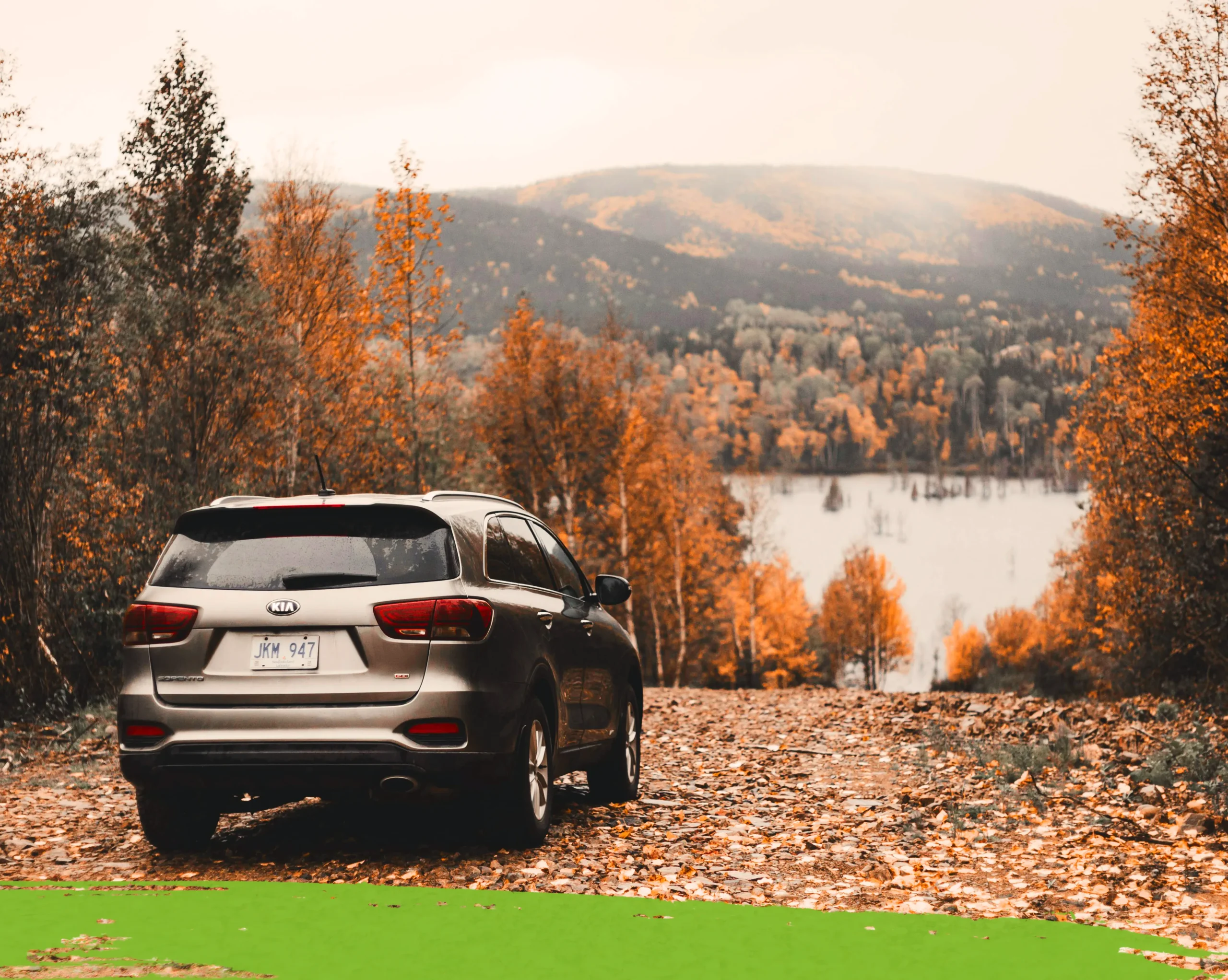 Car near a lake and forested area.